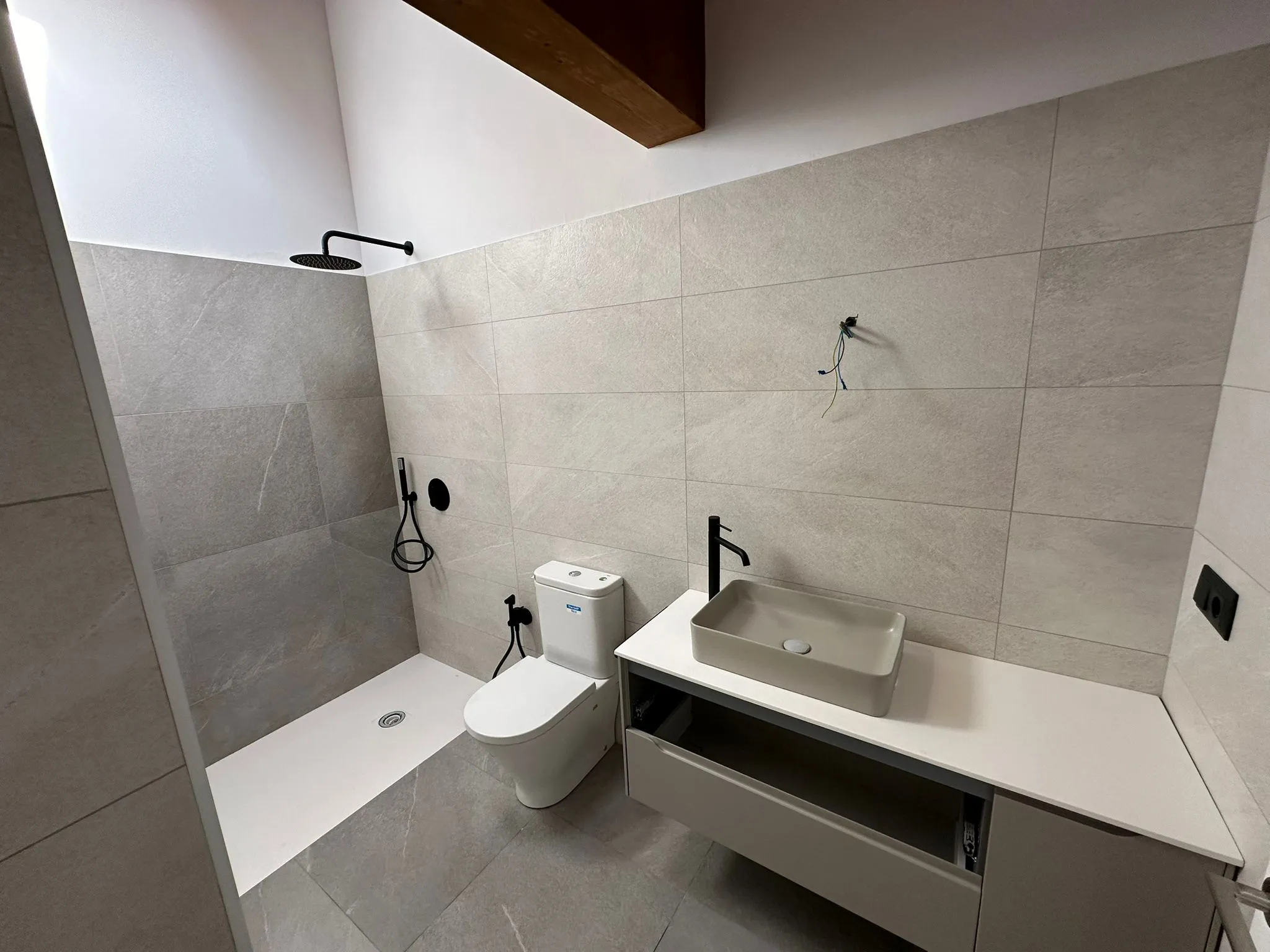 Baño abuhardillado con viga vista